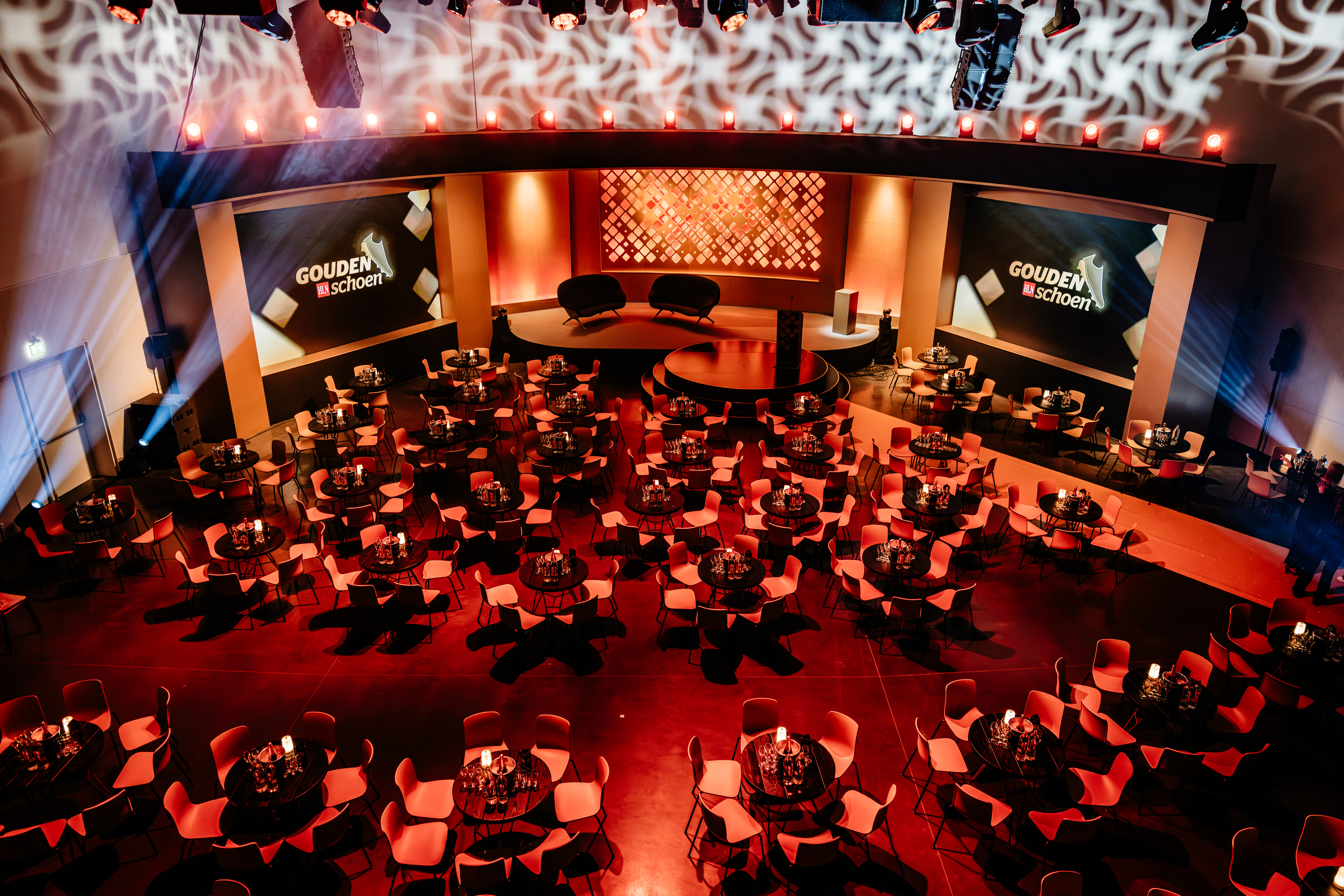 sdinneweth.be Zaal van het Gouden Schoen-gala met podiumdecor en ronde tafels, van bovenaf gezien